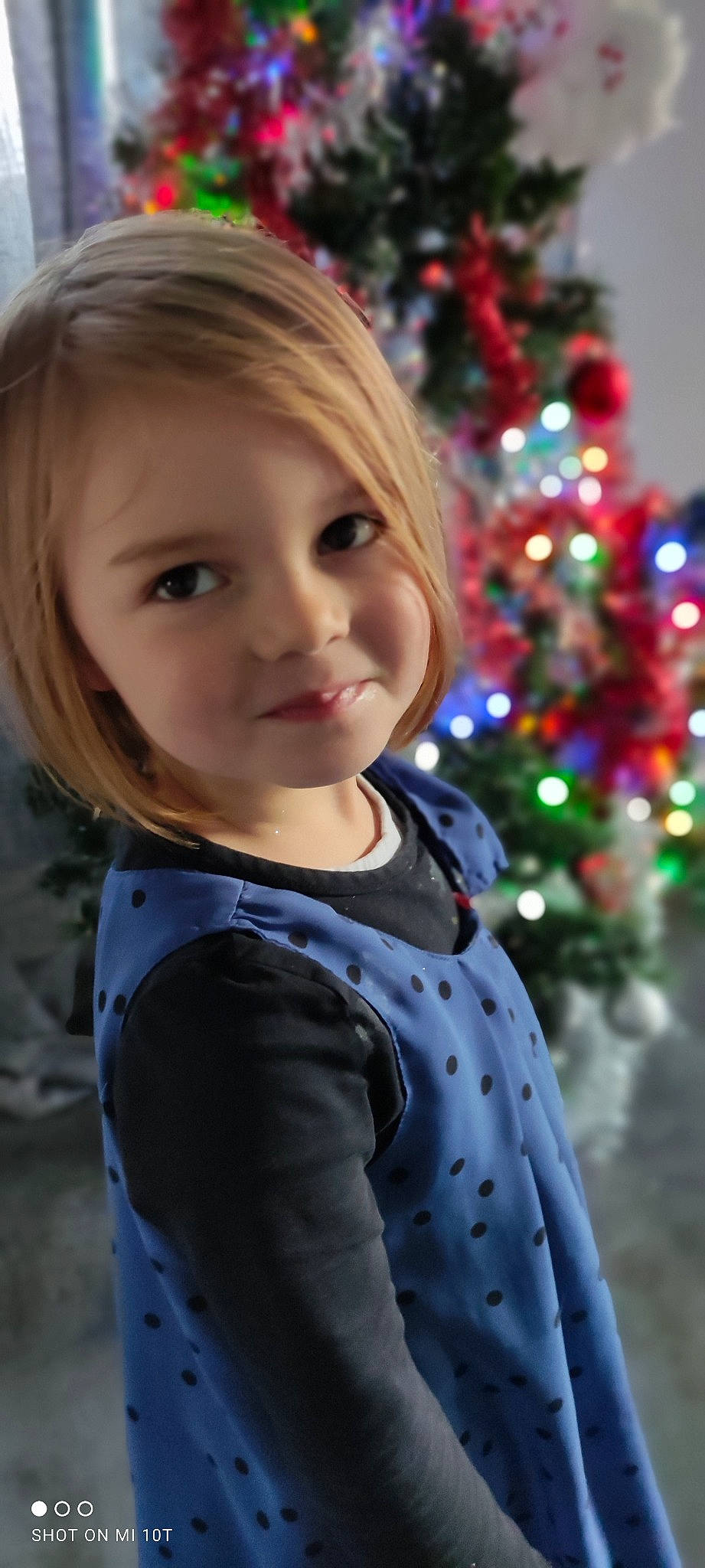 Lya a rejoint le concours — aidez-le/la à gagner de superbes lots ! baby_toddler_clothing, beauty, cheek, child, christmas_decoration, christmas_ornament, christmas_tree, evergreen, face, facial_expression, fun, hairstyle, happy, head, iris, people_in_nature, person, sleeve, smile, standing