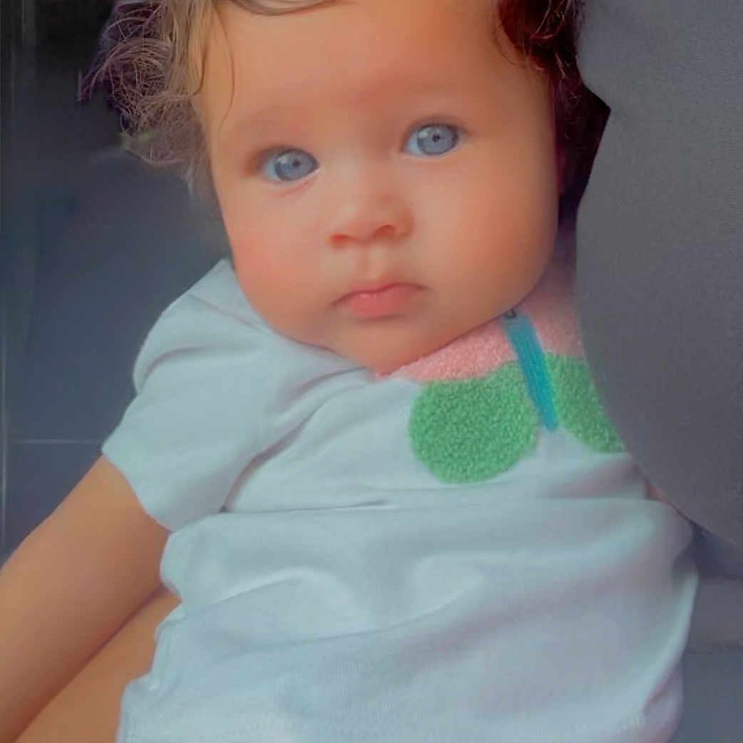 Nyella joined the competition — help win amazing prizes! baby, blue_eyes, butterfly_patch, child, closeup, clothing, curly_hair, cute, expression, face, holding, indoor, infant, person, pink_shorts, portrait, skin, toddler, white_shirt, young