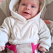 Tia participe au concours pour gagner de l'argent avec cette photo : baby, blue_eyes, buckle, cheeks, closeup, floral_background, hands, happy, harness, hood, hoodie, infant, newborn, pink, portrait, seat, smiling, soft_lighting, strap, white_clothing