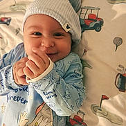 Elias is registered to the contest to win money with this photo: baby, smiling, blue_clothing, hat, tom_and_jerry, onesie, infant, cute, hands, lying_down, blanket, golf_theme, toy_carts, flag, happy, face, child, infant_clothing, indoor, portrait