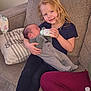 child, baby, bottle, feeding, couch, pillow, smile, happy, indoor, family, sibling, clothing, person, holding, infant, casual, home, relaxing, cute, love
