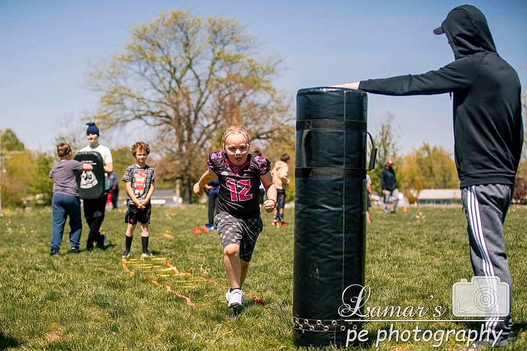 Malachi is registered to the contest to win money with this photo: child, running, sports, outdoor, grass, tree, field, practice, team, coach, activity, sunny, people, athlete, training, exercise, hoodie, shorts, shoes, ladder