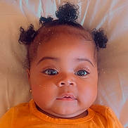 Saniya is registered to the contest to win money with this photo: adorable, baby, child, closeup, curly_hair, cute, drool, expressionless, eyelashes, face, head_and_shoulders, indoors, infant, lying_down, orange_clothing, portrait, puffy_cheeks, skin, small_earrings, soft_lighting