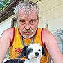 man, dog, pet, portrait, selfie, outdoor, porch, yellow_tank_top, chain_necklace, short_hair, beard, white_dog, black_dog, furniture, wooden_chair, window, mop, expression, casual, summer