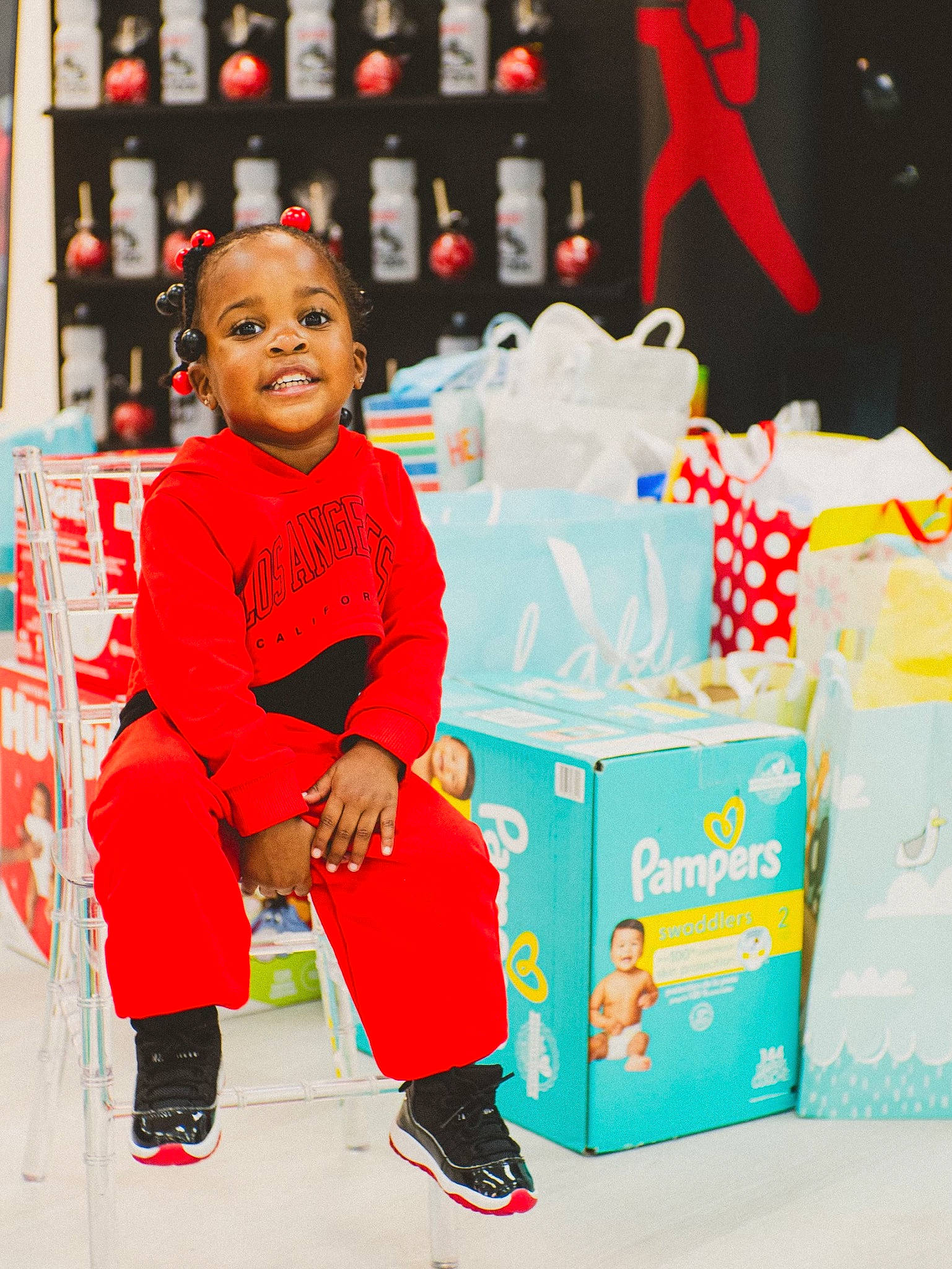 Danni is registered to the contest to win money with this photo: box, carmine, carton, child, convenience_store, event, flooring, fun, happy, holiday, logo, packaging_and_labeling, packing_materials, person, red, retail, room, shipping_box, sitting, smile