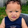 baby, backyard, blue_shirt, chair, child, closeup, clothing, curly_hair, dark_hair, daylight, face, firetruck, grass, happy, infant, outdoor, portrait, sitting, sleeveless, smiling