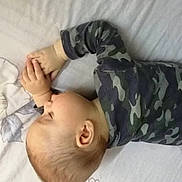 Patrick joined the competition — help win amazing prizes! baby, infant, child, lying_down, bed, pillow, bedding, camouflage, long_sleeves, gray_clothing, hands, fingers, face, head, ear, portrait, indoors, cozy, flower_pattern, sleeping