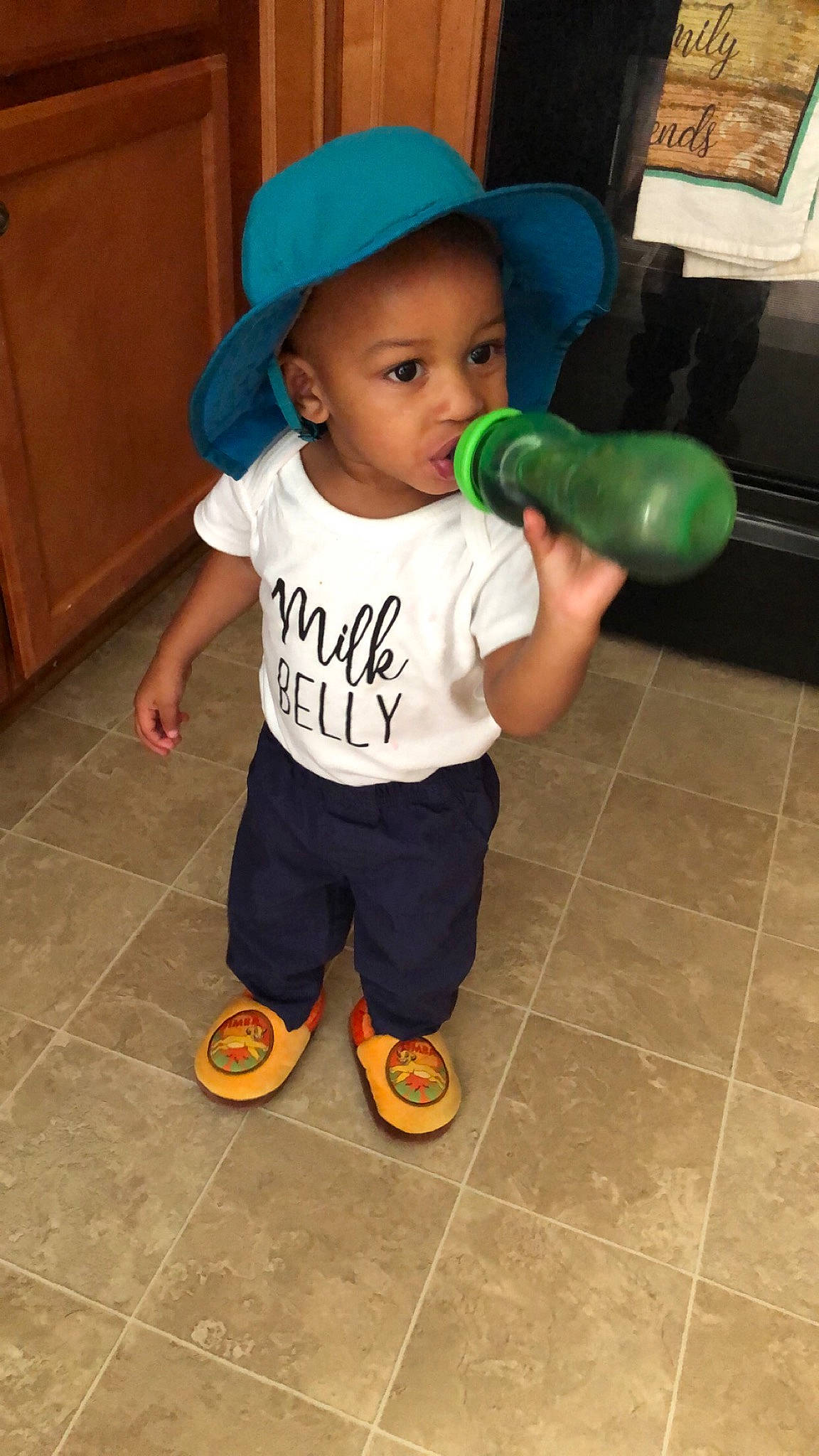 Teejay is registered to the contest to win money with this photo: baby, baby_products, baby_toddler_clothing, bottle, cabinetry, cap, child, drinkware, flooring, fun, happy, hardwood, hat, person, plastic_bottle, play, room, sleeve, standing, t_shirt