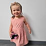 Athena a rejoint le concours — aidez-le/la à gagner de superbes lots ! casual, child, clothing, cute, floor, footwear, girl, happy, headband, indoors, person, pink_dress, plush_toy, portrait, sandals, smile, standing, toddler, wall, young_child