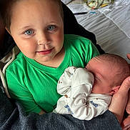 Malachi joined the competition — help win amazing prizes! child, baby, newborn, holding, green_shirt, bed, blanket, indoor, family, cuddle, portrait, person, infant, clothing, hand, cute, young, sleeping_baby, tender, soft_light