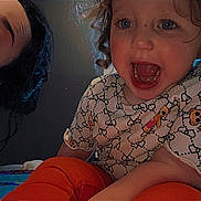 Sophia is registered to the contest to win money with this photo: child, toddler, adult, curly_hair, smiling, open_mouth, patterned_clothing, teddy_bear_pattern, indoor, window, bed, orange_pants, person, face, happy, curly_hair_child, casual_clothing, home, portrait, light