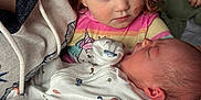 Sophia joined the competition — help win amazing prizes! child, baby, newborn, holding, sleeping, curly_hair, blue_eyes, pink_shirt, white_clothing, hand_holding, person, closeup, indoor, family, tender_moment, skin, face, caring, affection, hoodie