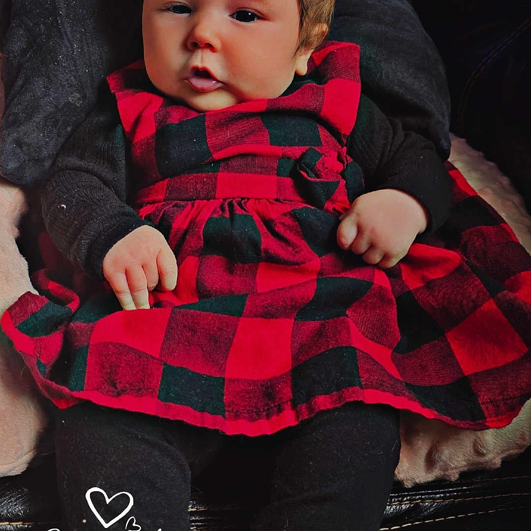Aizzley is registered to the contest to win money with this photo: baby, black, blanket, checkered, child, clothing, cozy, cute, dress, expression, feet, indoors, infant, legs, portrait, red, sitting, timestamp, warm, weekend