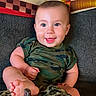 baby, infant, child, smiling, happy, sitting, couch, blanket, leopard_print, camouflage, clothing, foot, barefoot, portrait, indoor, home, pillow, face, eyes, joy
