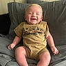 baby, smiling, child, onesie, bed, blanket, pillow, indoor, cute, happy, infant, clothing, person, portrait, candid, soft_lighting, skin, blond_hair, sitting, cozy