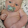 Roman is registered to the contest to win money with this photo: baby, pacifier, infant, cushion, patterned, indoor, curious, skin, hand, face, blue_eyes, light_hair, diaper, comfort, relaxing, child, person, portrait, closeup, home