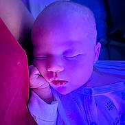Emilia is registered to the contest to win money with this photo: baby, sleeping, infant, purple_light, pajamas, hand, face, peaceful, cushion, red, closeup, indoors, soft_light, newborn, resting, portrait, child, cute, cozy, skin