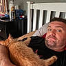 Casmo is registered to the contest to win money with this photo: man, cat, bed, pillow, blanket, furniture, indoor, relaxing, orange_cat, sleeping_cat, facial_hair, black_shirt, wooden_headboard, nightstand, can, tissue_box, container, casual, resting, home