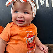 Danielle is registered to the contest to win money with this photo: autumn, baby, background, blue_eyes, child, closeup, clothing, cute, face, fall, hand, headband, holiday, orange_shirt, person, portrait, pumpkin, seasonal, sitting, smiling