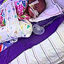 newborn, baby, incubator, hospital, medical_tubes, blanket, pacifier, swaddled, face, infant, bed, healthcare, patient, tape, premature, clothing, lying_down, purple, white, striped