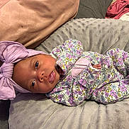 Love is registered to the contest to win money with this photo: baby, newborn, infant, pink_bow, floral_clothing, onesie, cushion, blanket, sleepwear, soft_texture, lying_down, headband, cute, infant_face, closeup, indoors, child, portrait, baby_girl, resting