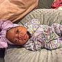 baby, newborn, infant, pink_bow, floral_clothing, onesie, cushion, blanket, sleepwear, soft_texture, lying_down, headband, cute, infant_face, closeup, indoors, child, portrait, baby_girl, resting