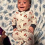 baby, blanket, child, comfort, cute, face, footed_pajamas, fox_pattern, hand, happy, head, indoors, infant, lying_down, onesie, portrait, sleepwear, smiling, soft_texture, young_child