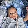 baby, blanket, blue_eyes, child, closeup, clothing, cloud_pattern, cozy, cute, expression, fabric, face, happy, infant, lying_down, portrait, raised_arm, shirt, sleeping_bag, smile