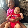 Koah is registered to the contest to win money with this photo: baby, blanket, child, couch, cozy, curly_hair, cute, family, fourth_of_july, happy, indoor, infant, laughing, pink_bow, playful, portrait, red_onesie, sitting, smiling, toddler