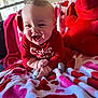 Zaylen joined the competition — help win amazing prizes! baby, smiling, red_clothing, teddy_bear, blanket, heart_pattern, indoors, couch, child, happy, cute, plush_toy, soft_texture, infant, person, portrait, cozy, home, red, playful