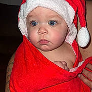 Zaylen is registered to the contest to win money with this photo: baby, child, face, blue_eyes, red_towel, santa_hat, wrapped, cute, portrait, infant, skin, hand, tattoo, expression, indoor, person, closeup, holiday, christmas, soft
