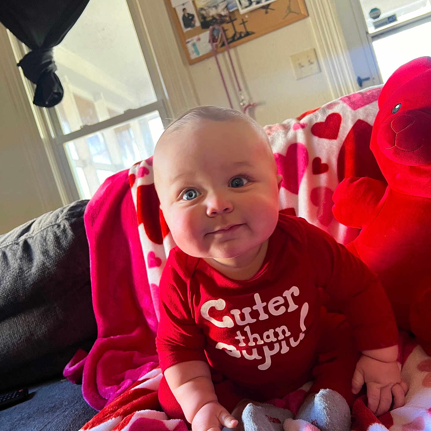 Zaylen is registered to the contest to win money with this photo: baby, blanket, child, couch, cozy, cute, face, furniture, heart_pattern, home, indoor, infant, person, portrait, red_clothing, sitting, smiling, soft_toys, teddy_bear, window