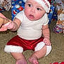Zaylen is registered to the contest to win money with this photo: baby, child, christmas, holiday, santa_hat, red_clothing, white_shirt, carpet, gift_wrap, presents, festive, indoors, cute, hand_holding, expression, sitting, holiday_season, celebration, toddler, face