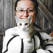 Chouquette a rejoint le concours — aidez-le/la à gagner de superbes lots ! affection, braided_hair, brown_cat, cat, closeup, cozy, cute, female, glasses, holding, indoor, knitted_sweater, person, pets, portrait, smiling, striped_sweater, warm, white_cat, wooden_background