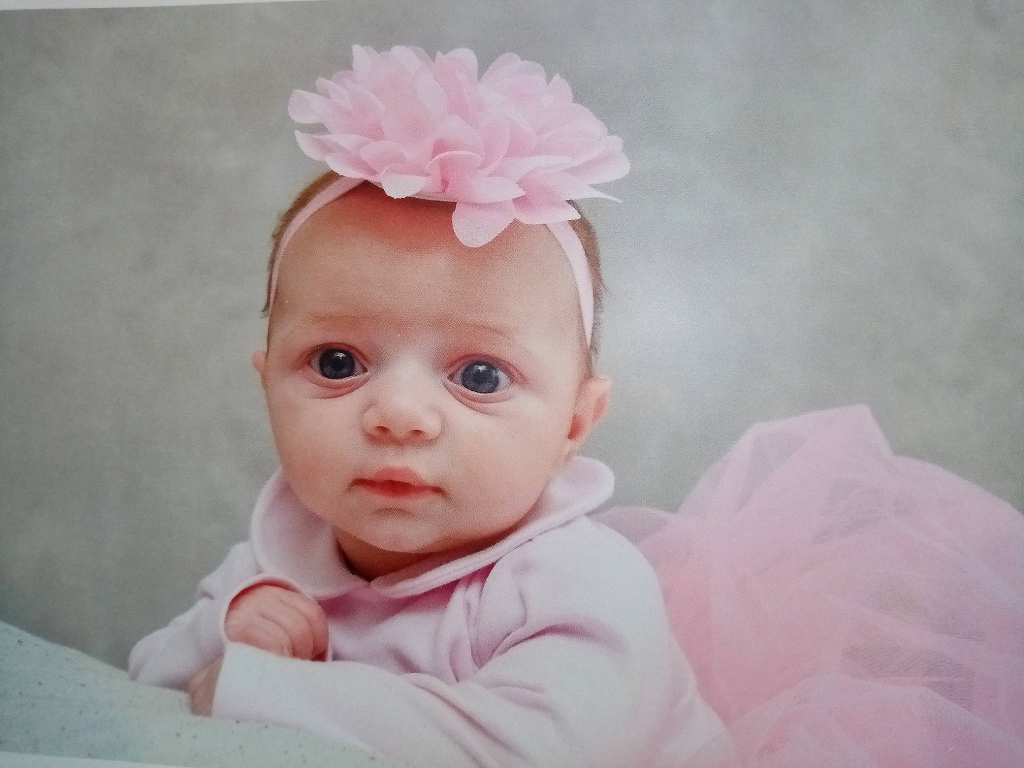 Melya participe au concours pour gagner de l'argent avec cette photo : baby, baby_toddler_clothing, cheek, chin, dress, eyebrow, flash_photography, flower, hair_accessory, happy, head, headgear, iris, lip, magenta, person, petal, pink, skin, sleeve