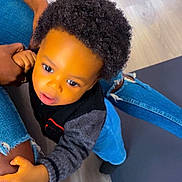 Noah a rejoint le concours — aidez-le/la à gagner de superbes lots ! toddler, child, curly_hair, indoor, floor, jeans, hand, leg, sweater, black_clothing, person, skin, footwear, yellow_sock, denim, casual, cute, exploring, holding, candid