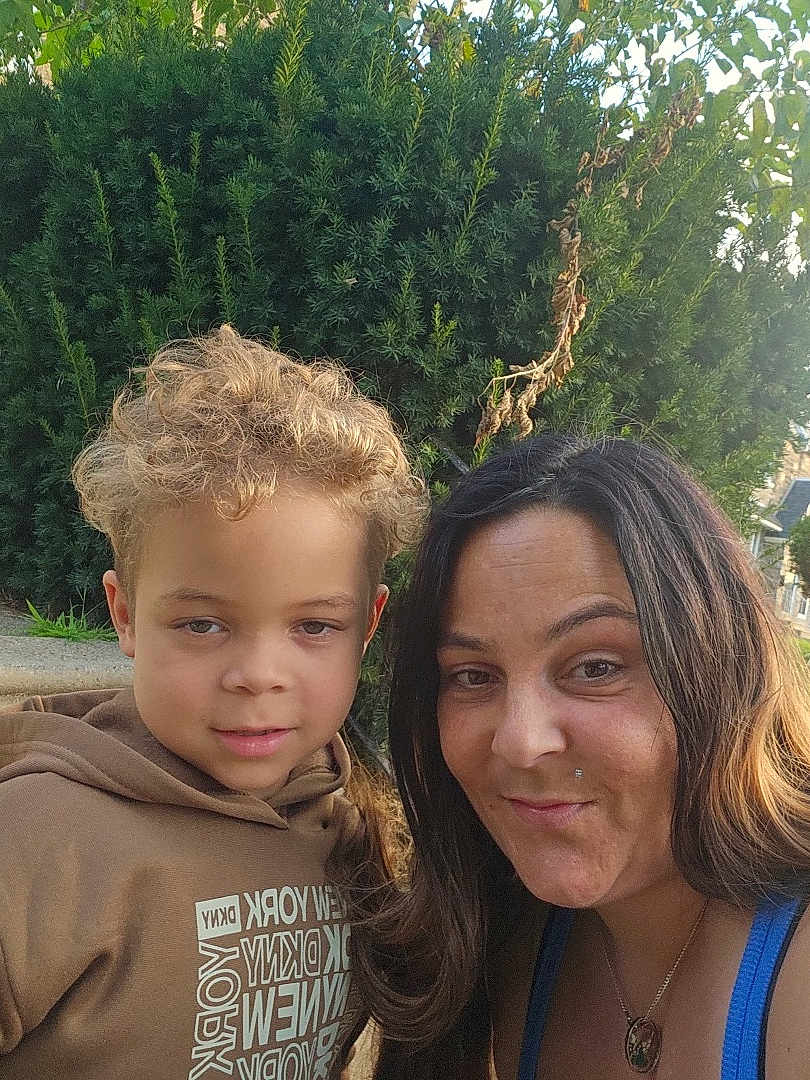 Keyon Carter is registered to the contest to win money with this photo: child, woman, smile, outdoor, greenery, bush, portrait, happy, casual_clothing, curly_hair, necklace, daylight, face, nature, people, headshot, family, toddler, hoodie, selfie