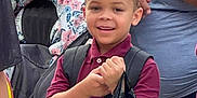 Keyon Carter is registered to the contest to win money with this photo: child, boy, smiling, backpack, plastic_bag, maroon_shirt, crowd, people, outdoor, group, hair, person, casual_clothing, daylight, holding, young, happy, school, water_bottle, multicultural
