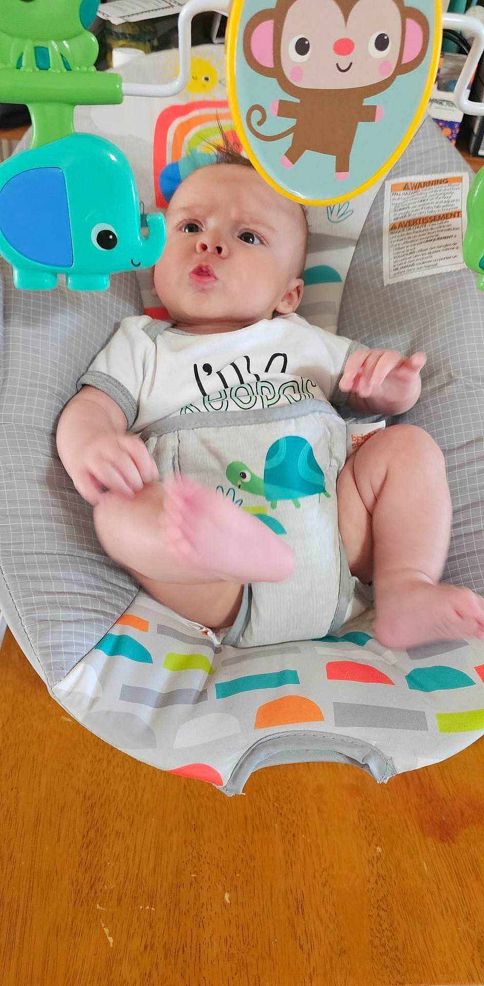 Ace is registered to the contest to win money with this photo: baby, baby_products, baby_toddler_clothing, cheek, child, green, happy, linens, pattern, person, pink, play, product, room, sitting, sleeve, sock, t_shirt, textile, toddler