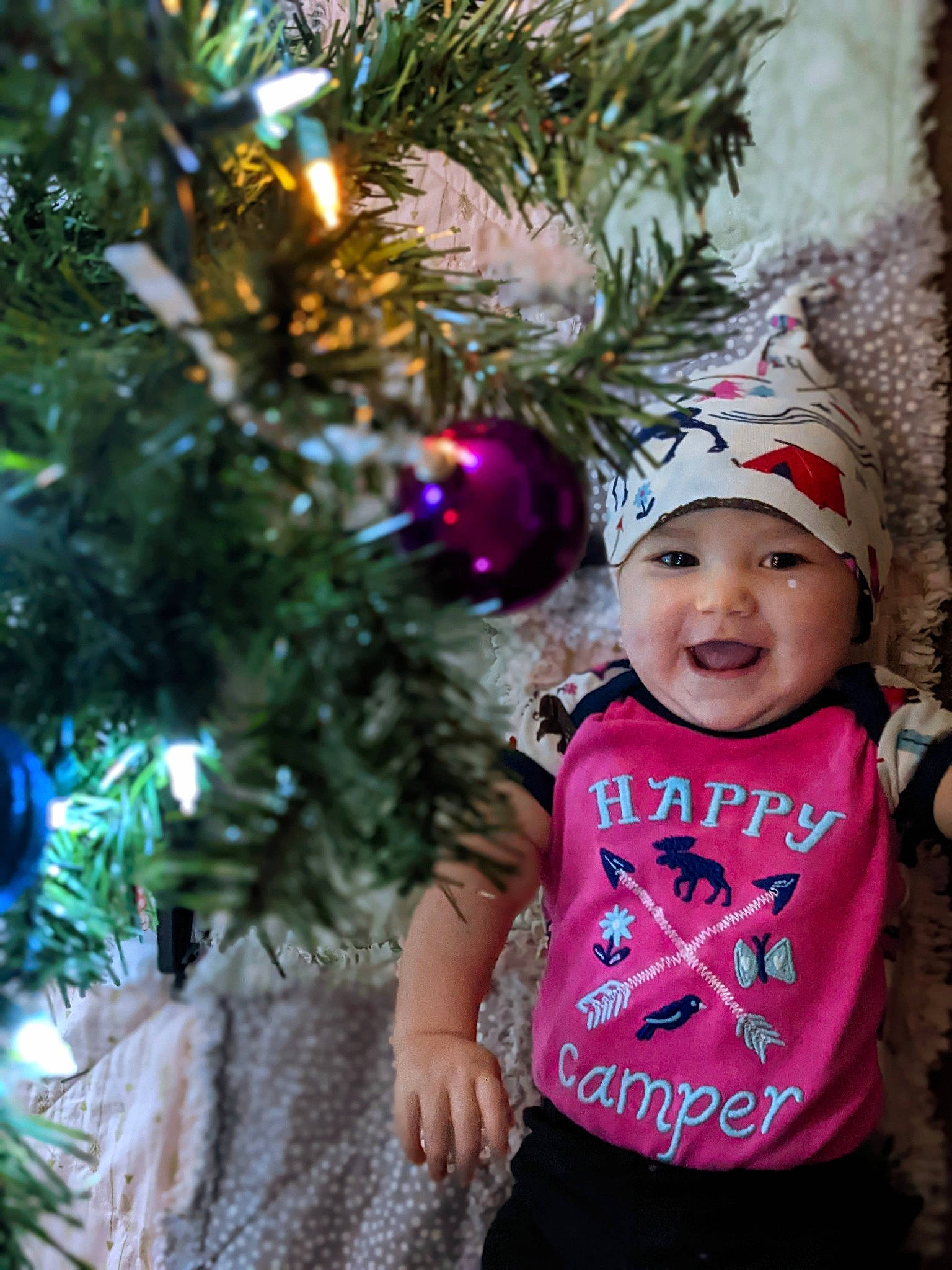 Nyx is registered to the contest to win money with this photo: baby, baby_toddler_clothing, branch, cap, christmas, christmas_decoration, christmas_ornament, christmas_tree, event, evergreen, happy, headwear, holiday, holiday_ornament, joy, ornament, person, plant, smile, t_shirt