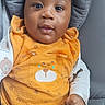 Elia participe au concours pour gagner de l'argent avec cette photo : baby, child, infant, orange_outfit, bear_design, cushion, gray, smile, face, eyes, hand, clothing, seated, indoors, cute, portrait, happy, young_child, person, baby_clothes