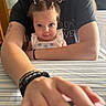Raylon is registered to the contest to win money with this photo: baby, child, adult, person, table, hand, hair, pigtails, bracelet, tattoo, shirt, indoor, portrait, curious, smile, skin, face, arm, holding, closeup
