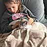 blanket, casual_clothing, cat, child, comfort, couch, cozy, domestic, fur, girl, hand, hoodie, indoor, living_room, nike_logo, pet, portrait, relaxed, sitting, snuggling