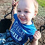 child, boy, smiling, swing, playground, outdoors, grass, blue_tshirt, shirt_text, camouflage_pants, close_up, portrait, spiky_hair, teeth, holding_chain, seat, chain, candid, sunlight, playtime