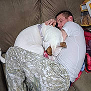 Diamond joined the competition — help win amazing prizes! dog, man, sleeping, couch, blanket, pet, companion, indoors, cozy, nap, resting, white_dog, brown_ears, collar, cuddle, living_room, furniture, snacks, casual_clothing, portrait
