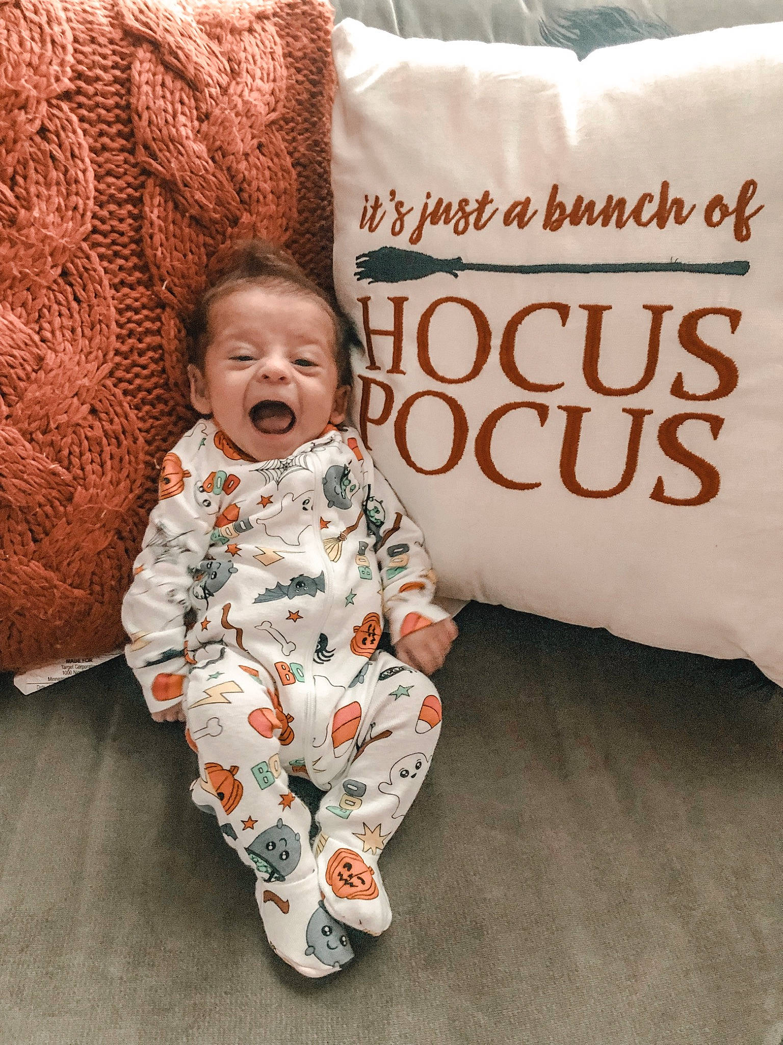 Westley is registered to the contest to win money with this photo: baby, baby_toddler_clothing, bedding, child, comfort, flooring, font, happy, linens, pattern, peach, person, pillow, portrait_photography, rectangle, room, sleeve, smile, textile, throw_pillow