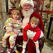 Owen is registered to the contest to win money with this photo: child, toddler, santa_claus, holiday, christmas, pajamas, red_clothing, beard, glasses, chair, decorations, wreath, lights, indoor, festive, floor, wood, portrait, people, smile