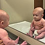 baby, infant, mirror, reflection, clinic, exam_table, diaper, hands, toes, legs, face, head, wall, door, medical_office, sitting, portrait, person, observation, healthcare