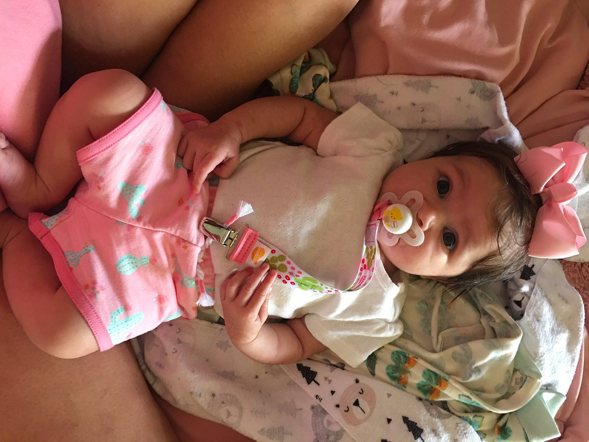 Nova is registered to the contest to win money with this photo: arm, baby, baby_toddler_clothing, cheek, chest, comfort, eye, facial_expression, finger, hand, human_body, joint, mouth, neck, person, pink, skin, stomach, textile, thigh