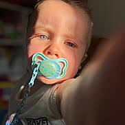 Augustin participe au concours pour gagner de l'argent avec cette photo : baby, blue_eyes, blurred_background, chain, child, closeup, cute, expression, face, heterochromia, indoor, infant, light, pacifier, person, portrait, selfie, shadow, skin, tank_top
